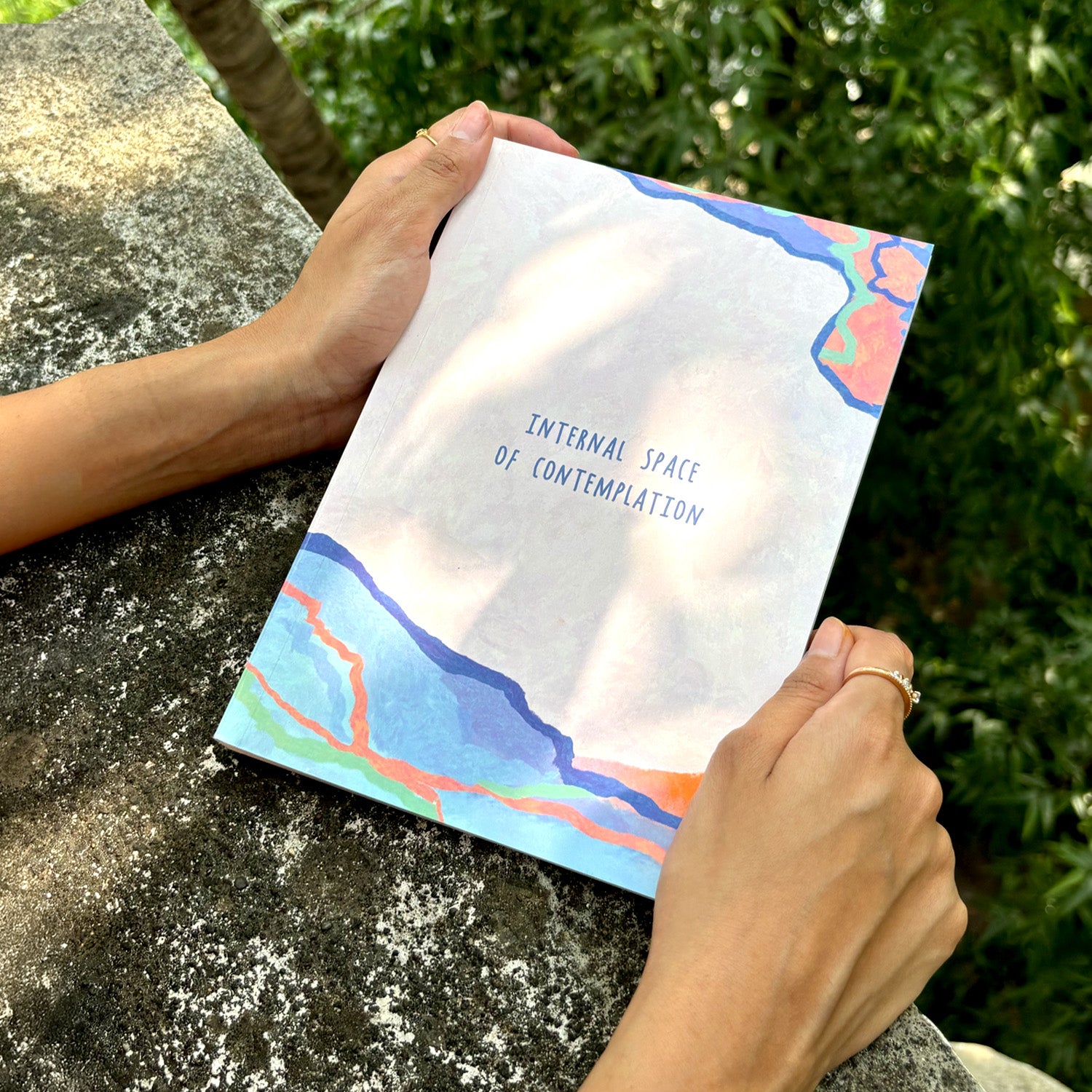 The image showcases the Internal Space notebook in the hands of a person, with trees and concrete in the background. 